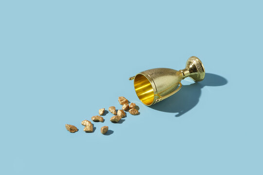 Turned golden bowl with precious stones scattered on surface