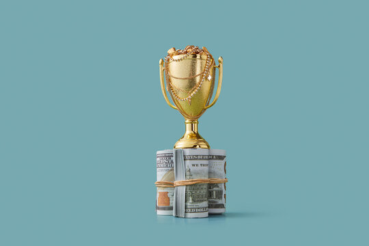 Golden winner cup filled with treasures on rolled up money