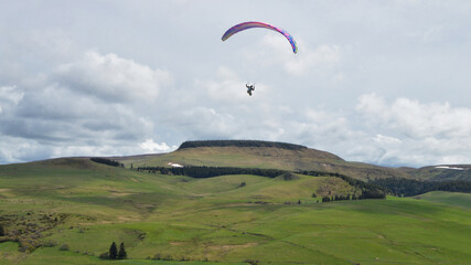 A paraglider flying over mountains in a mountainous landscape. It's an extreme sport.