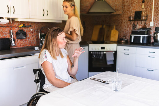 Woman with a Disability Enjoying Lunch with Assistant in Kitchen