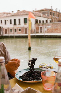Man eating pasta with cuttlefish ink in Venice, Italy
