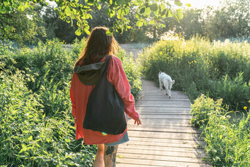 Woman Walking Dog on Nature Path at Sunset