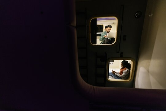 Male student watching laptop while woman using smartphone in hotel