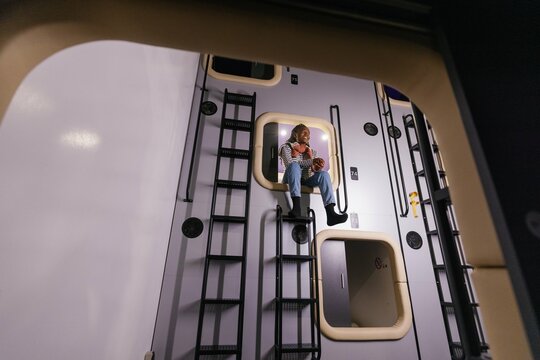 Bottom view of black woman at entrance of mini-room of capsule hotel