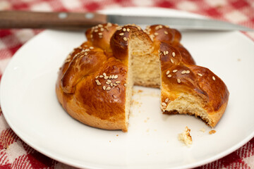 pan de día  de muertos cortado y porción mordida sobre plato blanco y mantel de fondo