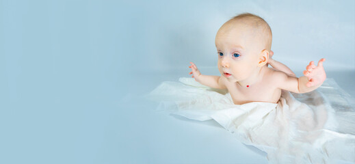 a baby with a hemangioma on his neck lies on a blue background. banner with a copy space. spread arms, the concept of flight