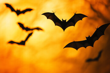 Naklejka premium Many black scary bats in motion against vibrant orange Halloween celebration background banner.