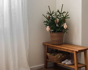 A basket with fir branches, blankets, slippers on a wooden bench in the hallway