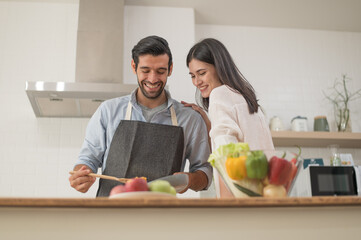 Happy young couple cooking together in the kitchen at home