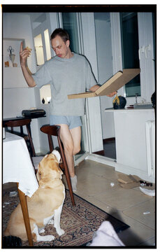 guy with pizza dancing in front of dog