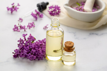Lilac essential oil. Spa oil with lilac flowers. Bottle with aroma oil and lilac flowers