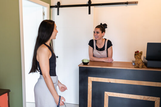 Dog groomer smiling and welcoming customer at reception desk