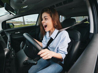 Woman driving a car, mouth wide open, hands on steering wheel, eyes wide in surprise, looking at the camera, capturing a moment of shock or excitement while driving