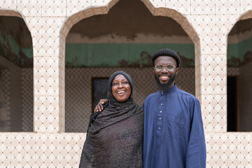 Smiling african muslim son holding his mother in front of mosque