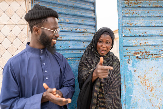 Muslim woman pointing with finger and smiling with man clapping hands