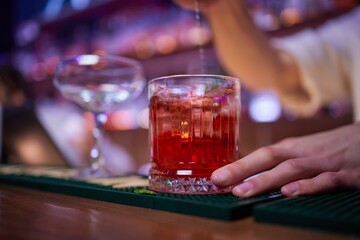Bartender pours pink cocktail into martini glass with flair