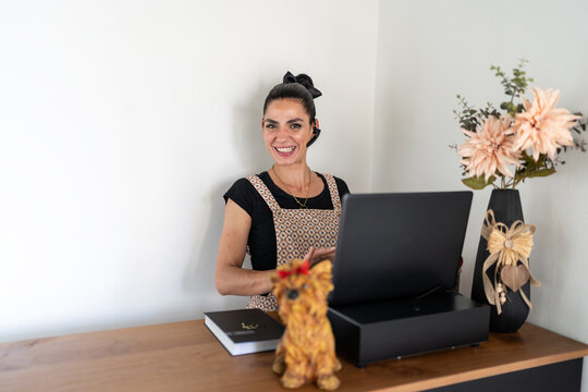 Smiling female pet groomer managing appointments using laptop