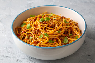 Pasta spaghetti bolognese with minced beef sauce, tomatoes, parmesan cheese and fresh basil in a plate