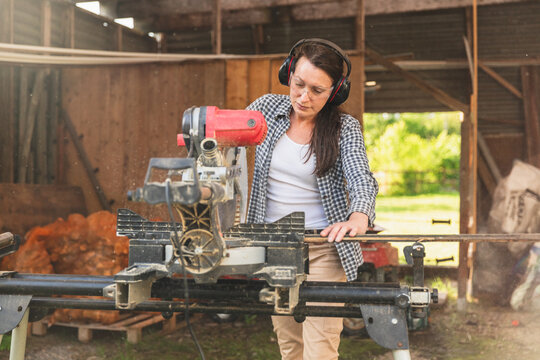 Concentrated Woman Cutting Wood with Table Saw in Garage