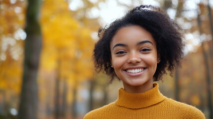 Portrait of young happy smiling black girl in autumn park, positive cheerful young woman enjoying a walk outdoors in autumn forest. Active lifestyle, good health. Enjoying outdoors.