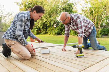Mature Couple Fixing Wooden Floor for summer