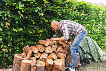 Man Standing by Stored Wood Ready for Chopping