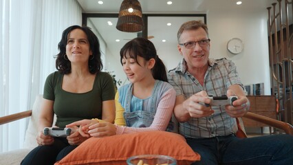 Grandfather, grandmother and granddaughter play console game as hobby. Old senior use technology activity communicate with new generation kid cross generation gap strengthen family bond. Divergence.
