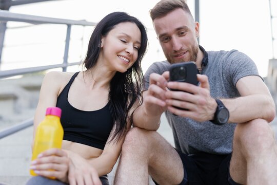 Close-up of two relaxed sports enthusiasts looking at smartphone 