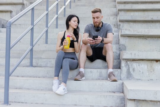 Sporty woman and her trainer discussing fitness program on stairs