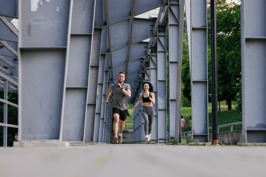 Fitness couple speeding up while running together in stadium path