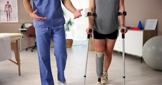 Physiotherapist, crutches and woman with prosthetic leg for walking, rehabilitation or help. Amputee patient, nurse and person with disability in clinic for medical, healthcare or talking for support