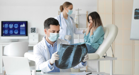 Young doctor with x-ray image of lungs in clinic