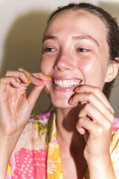 Woman flossing teeth, lo-fi, direct flash