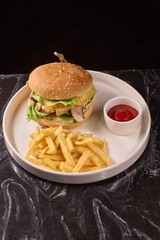 A Delicious Burger served with Crispy Fries and a side of Ketchup on a Dark Marble Table