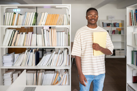 Student portrait holding a folder in library