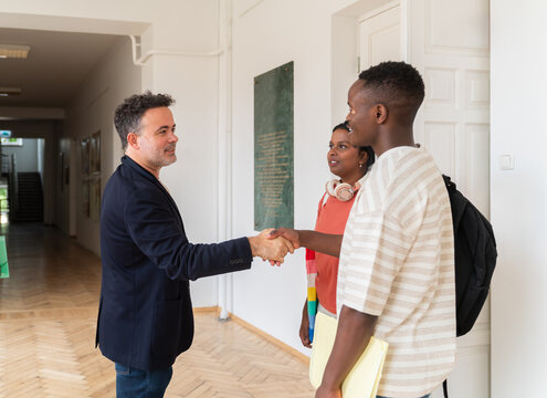 Professor and students handshake in university corridor