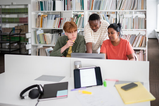 Three classmates studying together in library