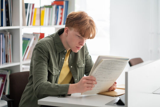 Student reading his notebook at library