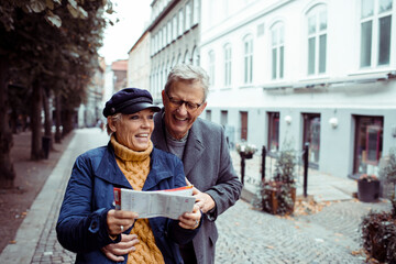 Senior couple laughing and exploring city with a map