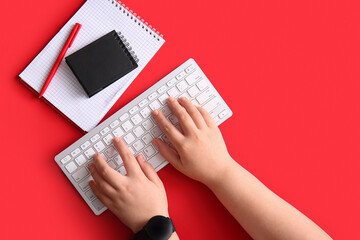 Female programmer using computer keyboard with notebooks on red background
