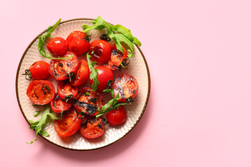 Plate with tasty grilled tomatoes and arugula on pink background