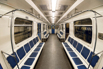 An empty car train subway with blue seats inside light interior. Taken with a fisheye lens