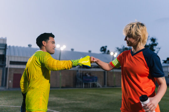Soccer players fist bumping during a football match.