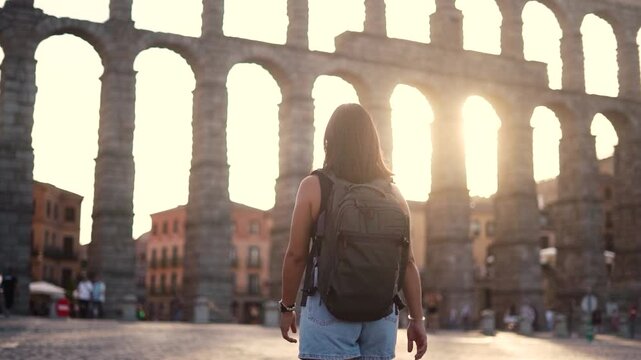 Aqueduct of Segovia visited by girl travelling to Spain walking arround this artichetectural structure which is considered as a world heritage.