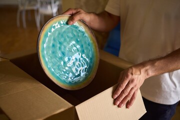 A man is unpacking boxes in his new home, organizing his belongings after relocation