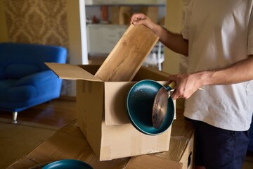 A man is unpacking boxes in his new home, organizing his belongings after relocation