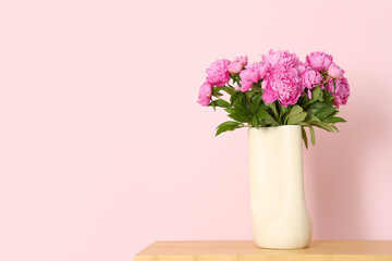 Vase of pink peonies on shelving unit near color wall