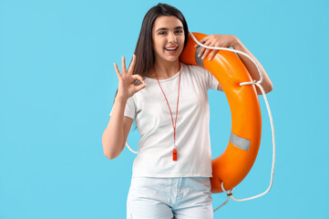 Female lifeguard with ring buoy showing OK on blue background