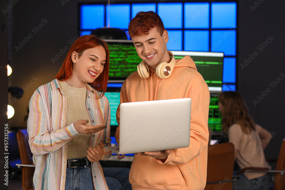 Sticker young programmers working with laptop in office at night