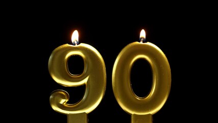 Golden number 90 birthday candle burning against a black background, creating a sleek and elegant celebration scene. - Powered by Adobe